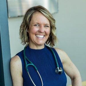Female Veterinarian with short blonde wavy hair wearing a sleeveless shirt and stethoscope