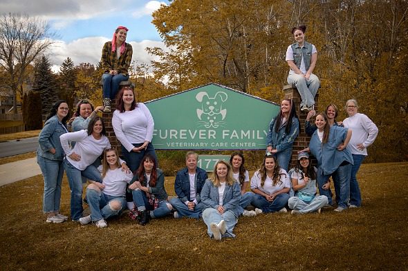 Furever Family Group Photo fo staff sitting around business sign