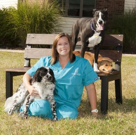 Doctor Kristin Hook sitting in the grass with her three dogs